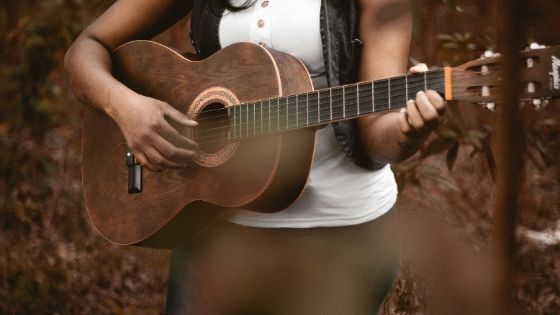 best way to record acoustic guitar at home - woman playing her acoustic guitar